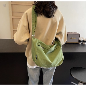 Detail of green pleated nylon crossbody bag featuring wide shoulder strap and black label
