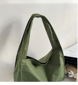 Détail du sac cabas à carreaux verts montrant la texture toile et les larges anses