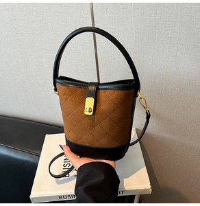 Détail du sac seau en daim marron avec matelassage en losange et fermoir rotatif doré