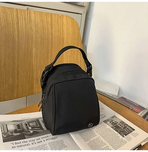 Detalle del mini bolso de nailon negro resistente al agua sobre mesa de madera