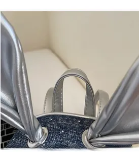 Detail of silver handle and cute bunny ear decor on blue denim backpack for students