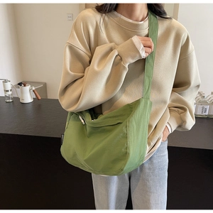 Detail showing grass green nylon messenger bag with wide strap and white zipper pull detail