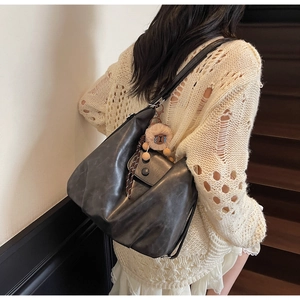 Dettaglio della grande borsa hobo in pelle scura con tasca laterale e ciondolo orsetto