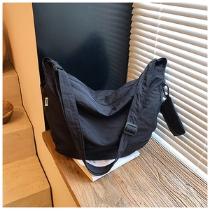 Detail of black dumpling bag with adjustable strap and small detachable zipper pouch