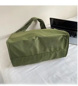 Détail de la texture douce du tissu à carreaux verts de ce sac cabas élégant
