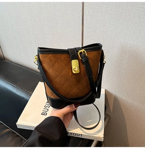Gros plan détaillé du motif matelassé et du fermoir doré sur le sac seau marron