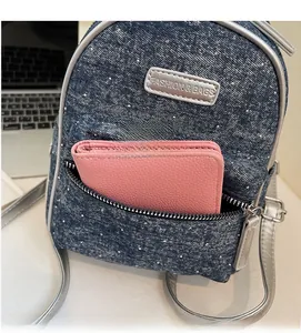 Detail of mini denim backpack with sequins and pink wallet showing interior capacity