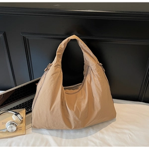 Macro shot of khaki pleated nylon tote bag with zipper details and lifestyle items