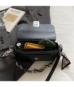 Detail of black crossbody bag showing interior storage capacity and silk scarf chain strap