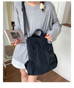 Detail of a black nylon backpack with multi-pocket design and adjustable straps for travel