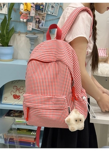 Détail du sac à dos en toile vichy rouge avec pendentif étoile et bretelles renforcées