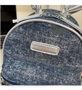 Detail of blue denim mini backpack with silver rabbit ear accents and dual zippers