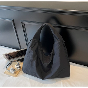 Detail shot of black wrinkled fabric on large tote bag with laptop and accessories