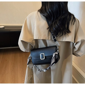 Detail view of black faux leather crossbody bag with silver buckle and silk scarf handle