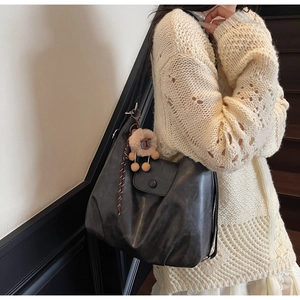 Dettaglio della borsa tote grigia in pelle con ciondolo alpaca e patta magnetica