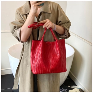 Detail of red leather woven tote bag showing luxury texture and spacious carryall design
