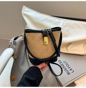 Détail du sac seau matelassé en daim kaki avec finitions en cuir noir et fermoir doré