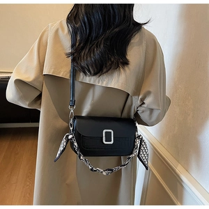Detail of black faux crocodile leather crossbody bag with scarf-wrapped chain handle