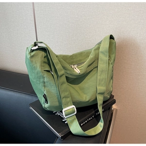 Macro detail of grass green pleated nylon crossbody bag with silver zipper and adjustable strap