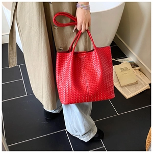 Detail of red woven leather tote bag with sturdy straps shown in a lifestyle setting
