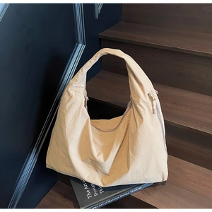 Close-up of the side zipper and textured beige fabric on the large canvas hobo bag