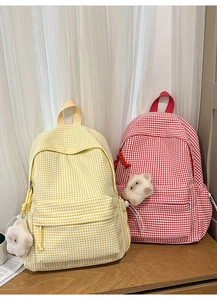 Détail de sacs à dos à carreaux jaune et rouge avec breloques d'ours pour étudiants
