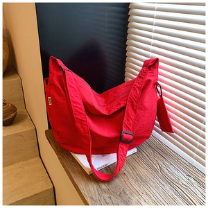 Close-up of red nylon half-moon bag with matching mini pouch on black display surface