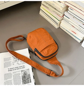 Detalle del bolso bandolera de nailon naranja con bolsillos con cremallera y correa