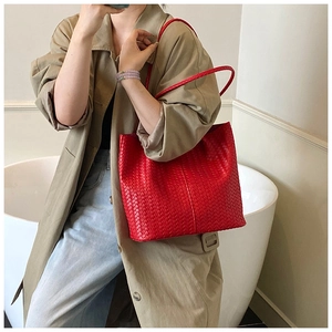 Detail shot of the red leather woven texture and shoulder strap on a large tote bag