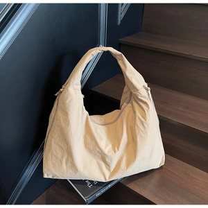 Detailed close-up of beige nylon tote bag with drawstring texture on wooden stairs