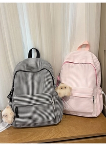 Détail de sacs à dos à carreaux en noir et rose avec des breloques étoile en peluche