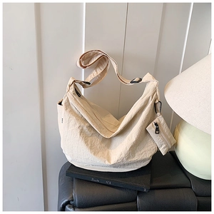 Close-up of cream nylon pleated crossbody bag with a detachable matching coin purse