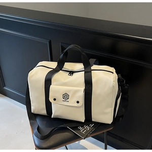 Detail view of large white travel bag with black straps and logo on a chair