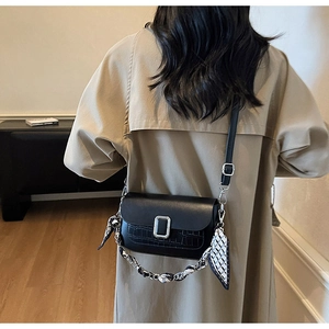 Close-up of black crocodile-embossed leather bag with silk scarf chain and silver buckle