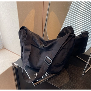 Minimalist black nylon crossbody bag with pleated texture and adjustable wide strap