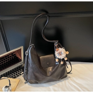 Dettaglio della borsa tote in pelle marrone scuro con chiusura magnetica e ciondolo di peluche