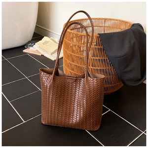 Detail of caramel brown woven leather tote bag with large capacity and Intrecciato texture