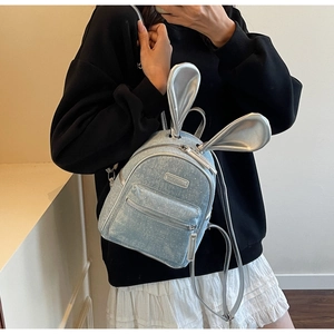 Detail of light blue glitter mini backpack featuring silver metallic bunny ears and logo
