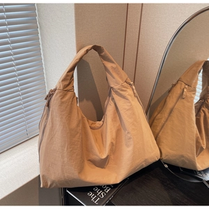 Detail of khaki nylon tote bag with multi-zipper design and mirror reflection lighting