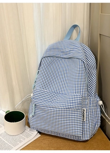 Détail du sac à dos à carreaux bleus et blancs avec poche zippée et cordon de serrage