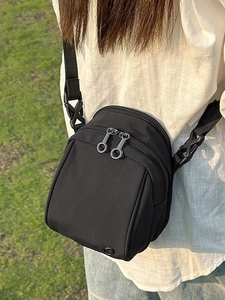 Bolso bandolera minimalista de nailon negro con doble cremallera usado en exterior casual