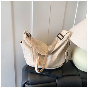 Close-up of beige nylon crossbody bag with pleated texture and mini side zipper pouch