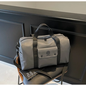 Detail of grey waterproof gym bag with MING JIA logo and black shoulder strap on leather seat