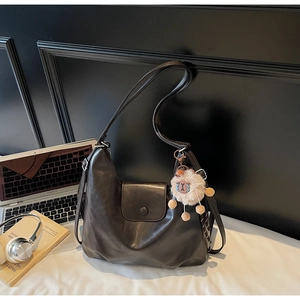 Dettaglio della borsa tote in pelle marrone con ciondolo a pecora e set di laptop