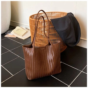 Detailed view of dark brown tote bag with premium woven leather texture and long straps