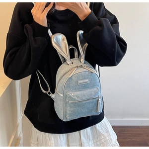 Detail of mini denim backpack with shiny silver bunny ears and front zipper pocket