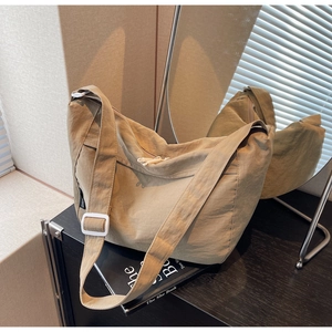 Detailed macro view of khaki pleated nylon texture and white strap buckle on crossbody bag
