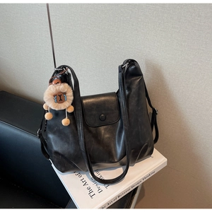 Dettaglio della borsa tote in pelle PU nera con chiusura magnetica e ciondolo a leone