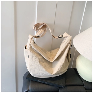 Detail of off-white dumpling bag with textured nylon fabric and adjustable wide shoulder strap
