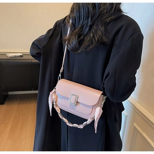 Detail of pink crossbody bag featuring croc pattern leather and silk scarf chain strap